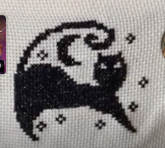gatito negro bordado en punto de cruz sobre tela blanca