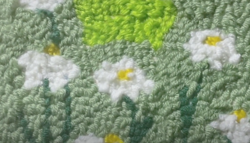 imagen de margaritas blancas con un fondo verde creado con punch needle