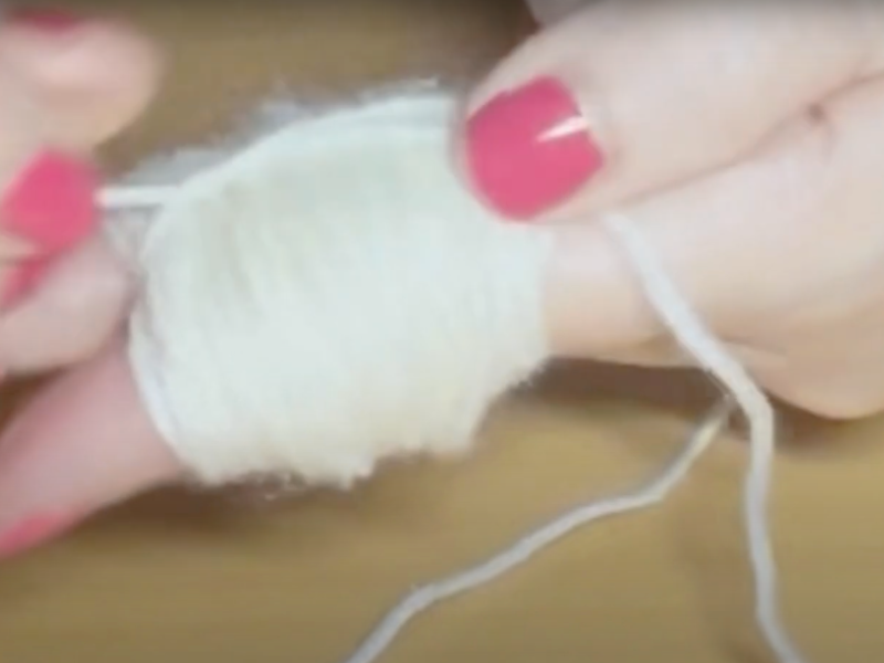 con ayuda de los dedos se hace un pompón de lana blanca