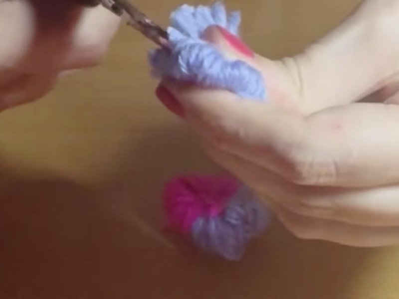 se abre el pompón morado con las tijeras