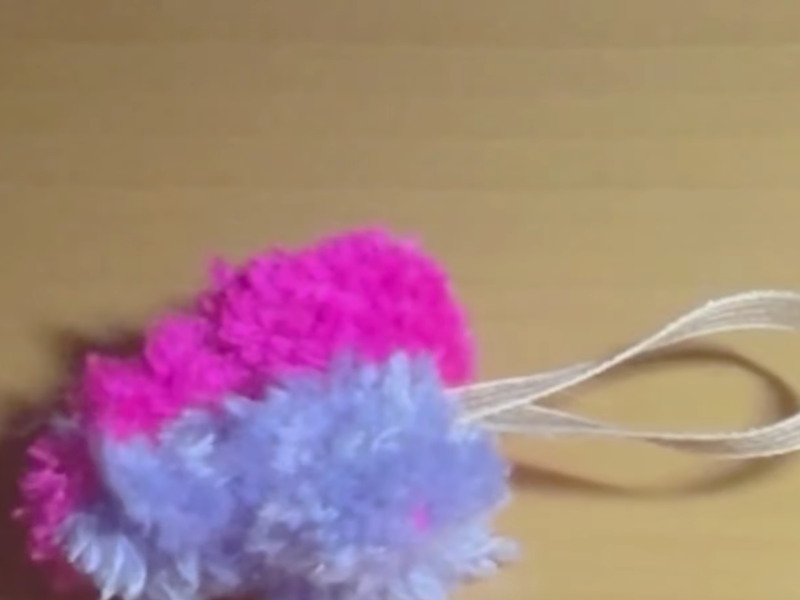 pompón en forma de corazón rosa y violeta con cinta para colgar